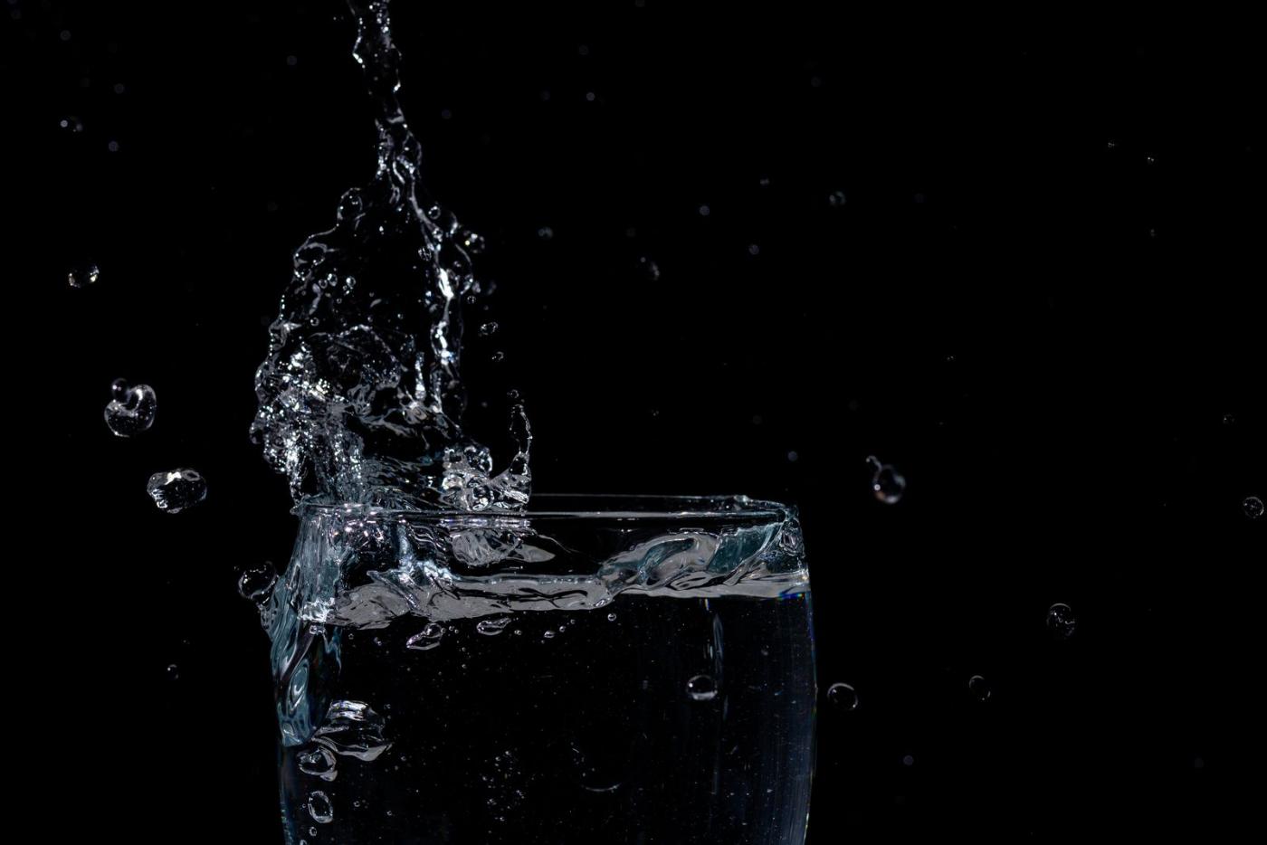 Wasser spritzt lebendig in ein Glas